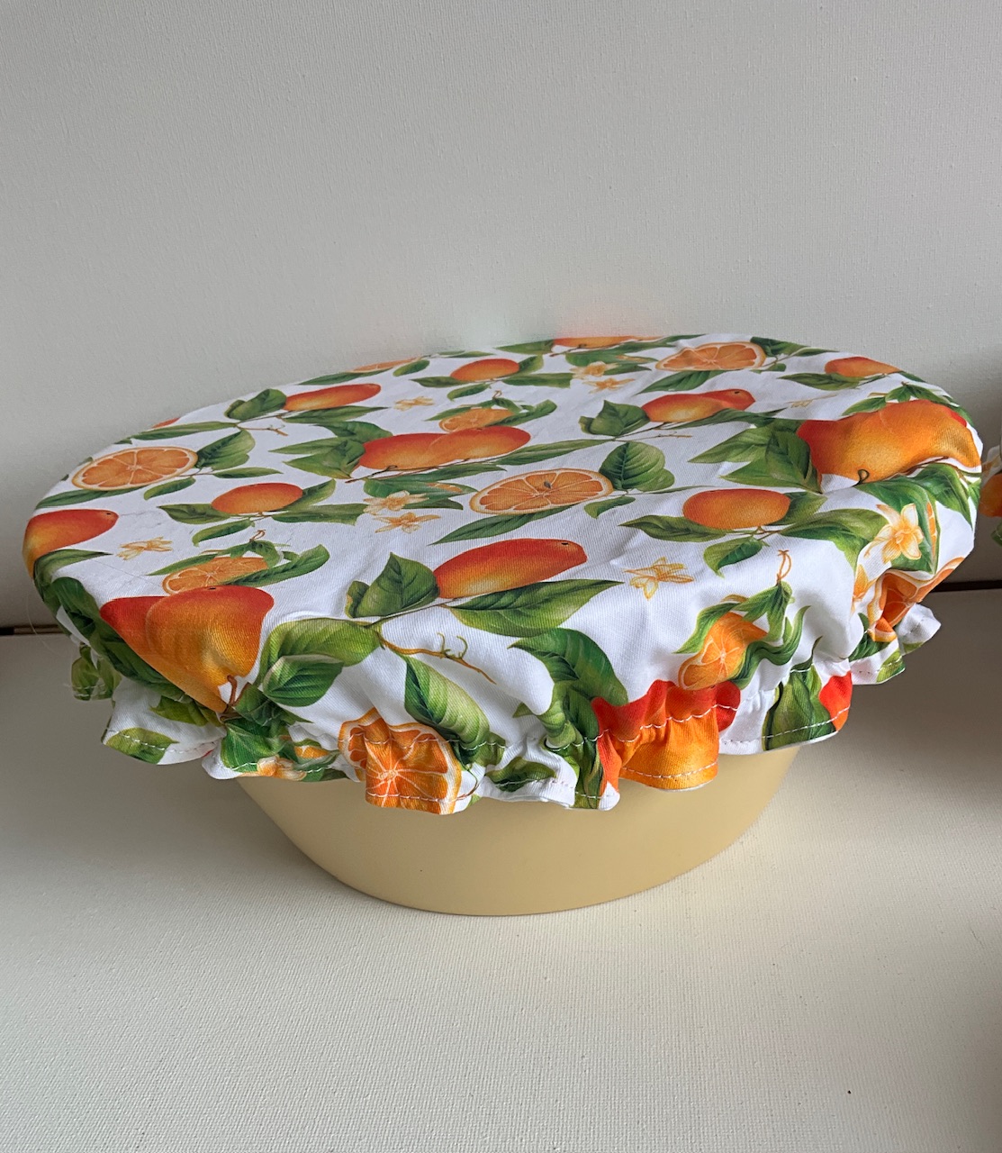 Charlotte couvre-plat motif grosses oranges et feuillage fond blanc en place sur un saladier
