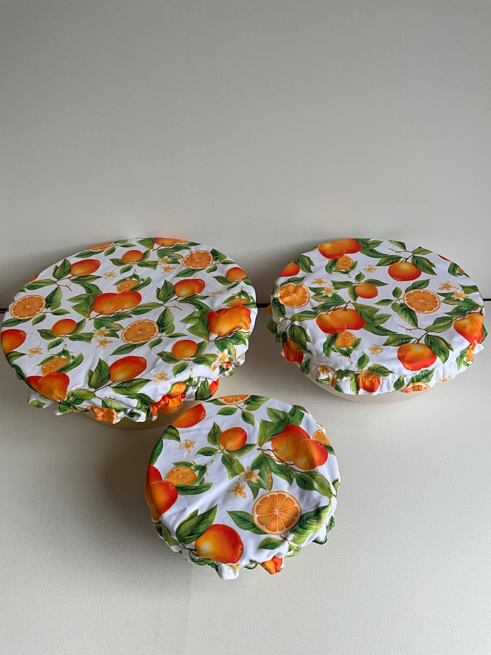 Les 3 charlottes couvre-plat Ø 18, 24 et 32 cm motif grosses oranges et feuillage fond blanc posées sur des saladiers