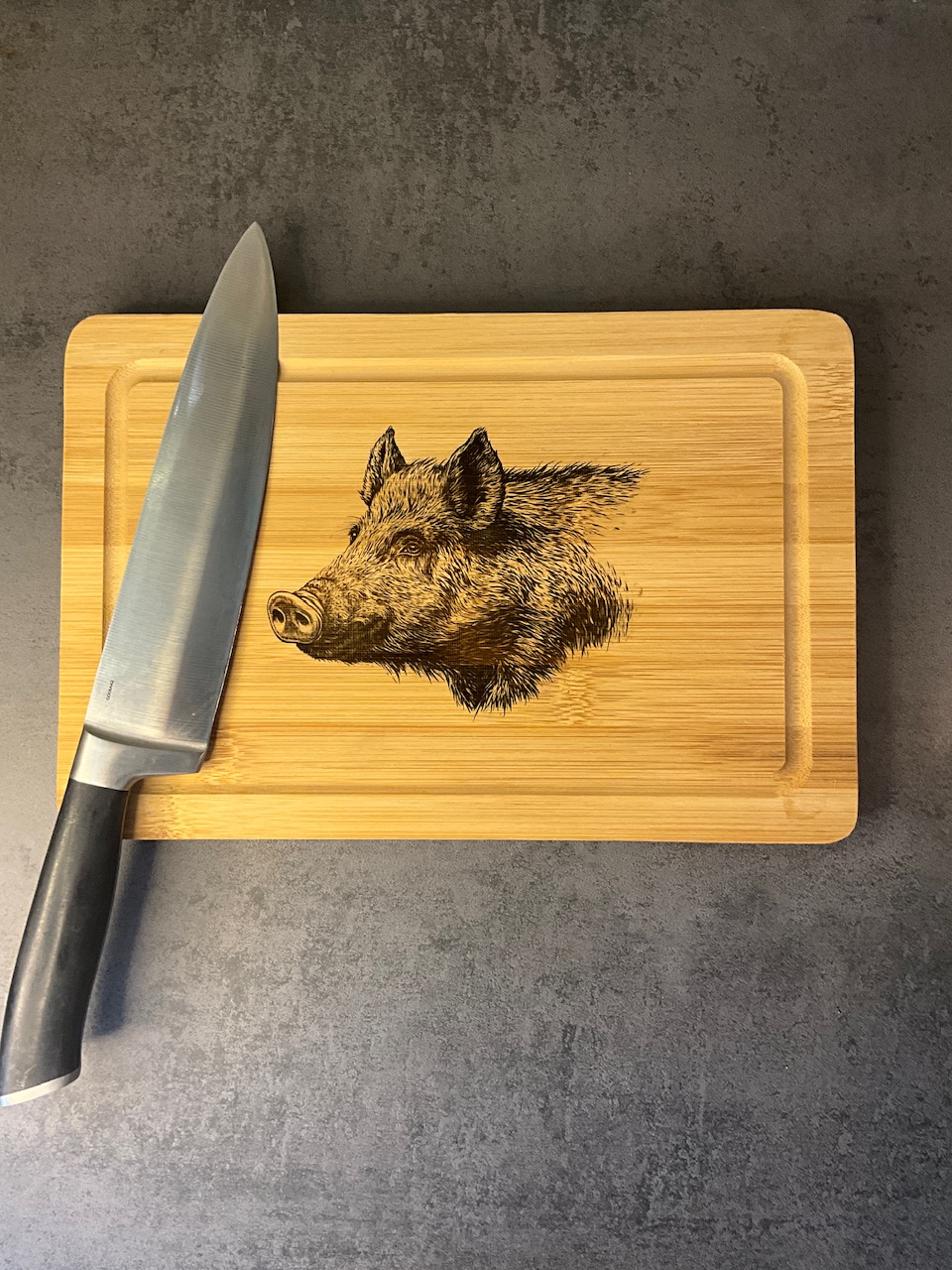 Planche à découper en bambou 30 × 20 cm gravée au laser motif sanglier, présentée avec un couteau de cuisine