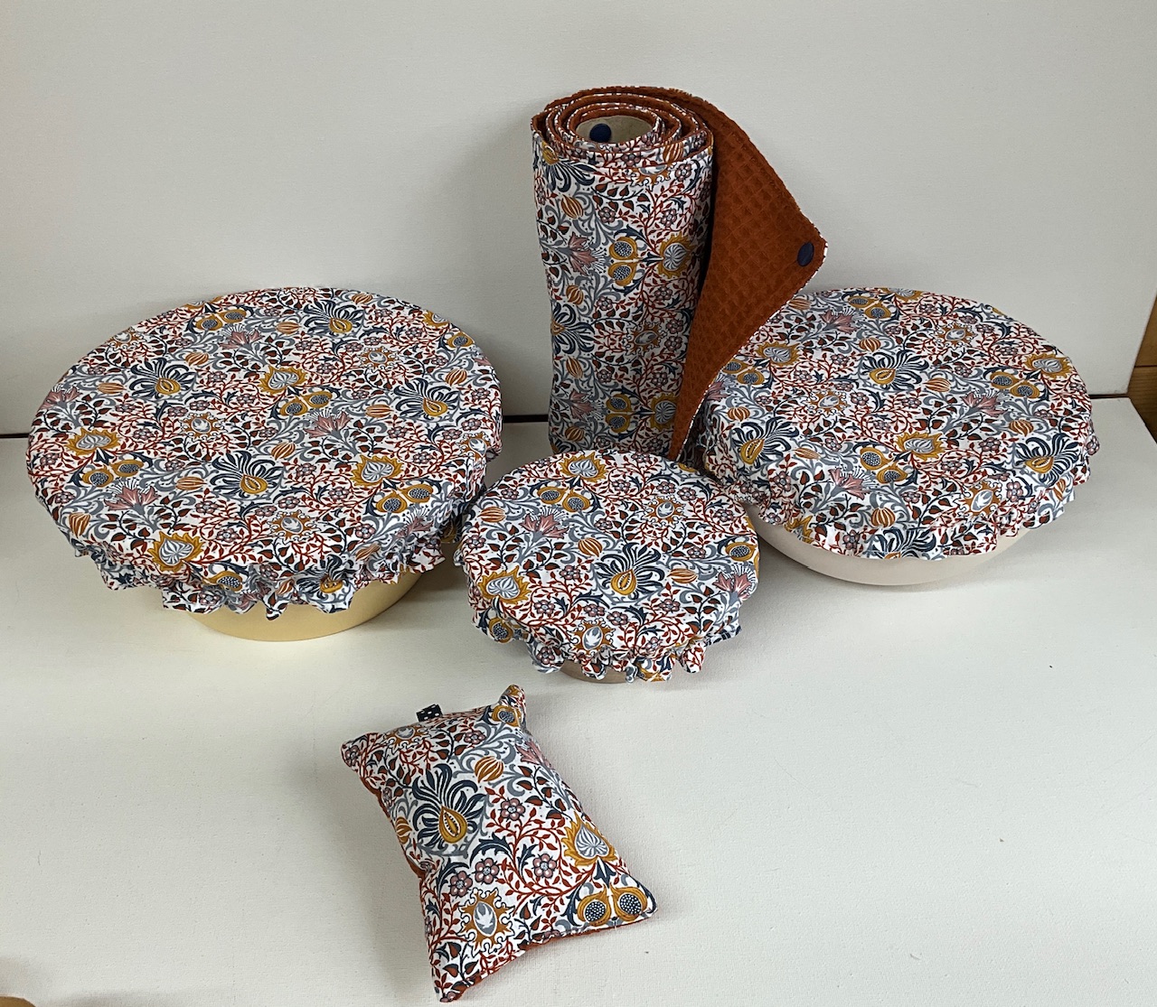 Ensemble de cuisine zéro déchet motif fleurs et feuillage ocre et bleu fond écru : 3 charlottes couvre-plat, 1 rouleau d’essuie-tout lavable et 1 éponge lavable, nid d’abeille terracotta