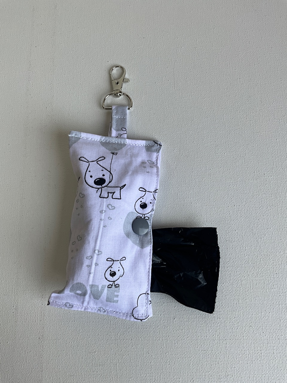Pochette à sacs à crottes motif chiens et cœurs fond blanc avec un sac à déjections sorti de la pochette, cousue main Sidonie Créa
