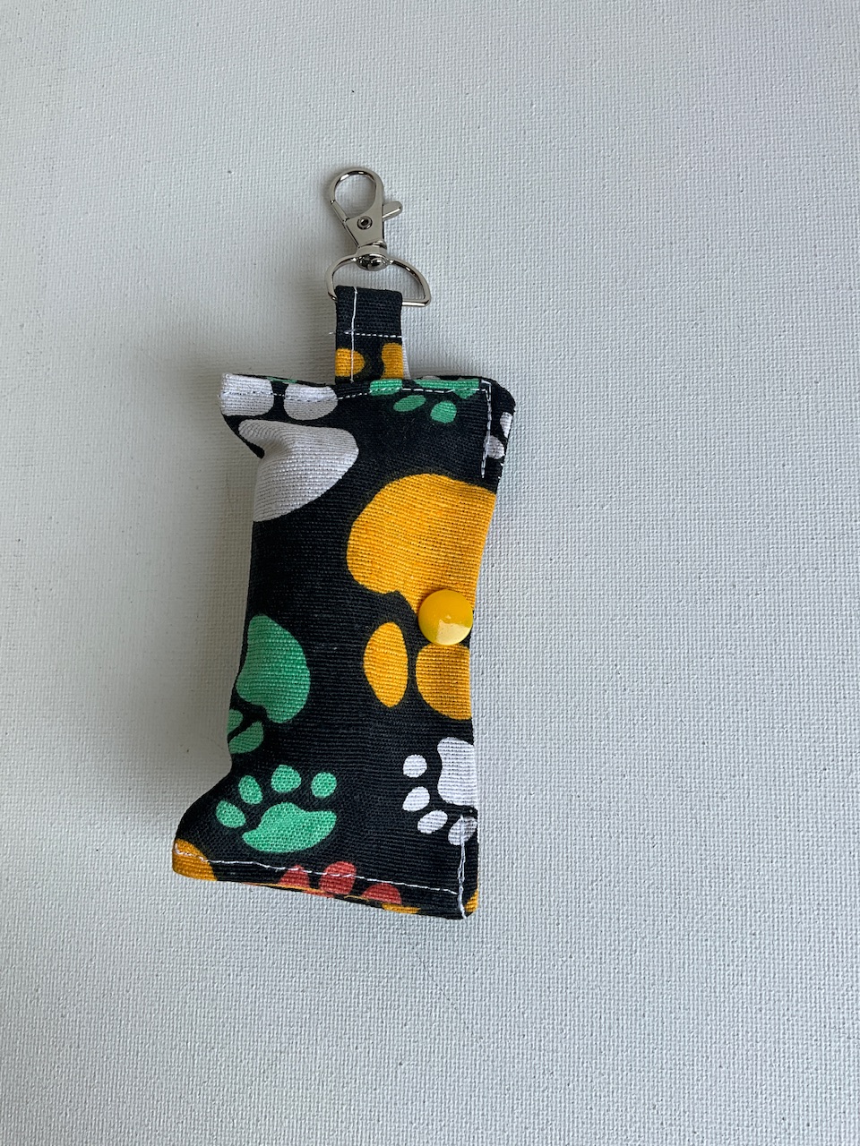Pochette à sacs à crottes pour chien en coton, motif grosses pattes multicolores fond noir, suspendue par son mousqueton, cousue main Sidonie Créa