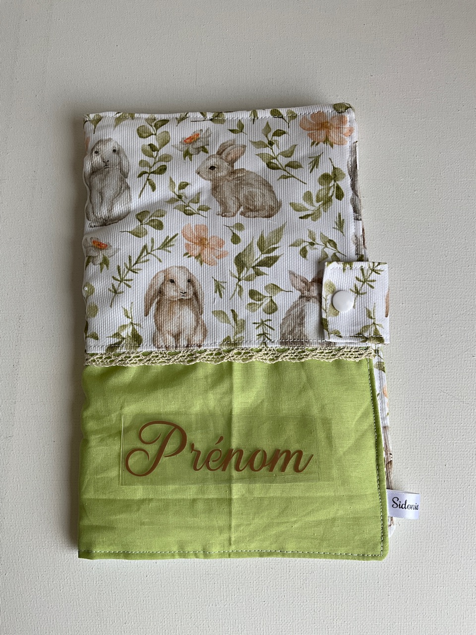 Protège carnet de santé personnalisable en coton lapins et eucalyptus fond écru – vu de face avec le prénom floqué, cousu main par Sidonie Créa