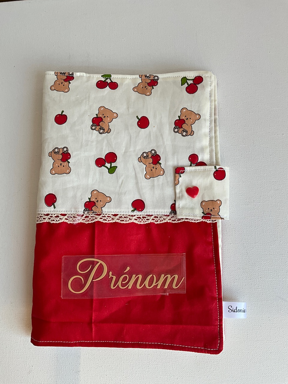 Protège carnet de santé personnalisable en coton oursons, pommes et cerises fond écru – vu de face avec le prénom floqué, cousu main par Sidonie Créa