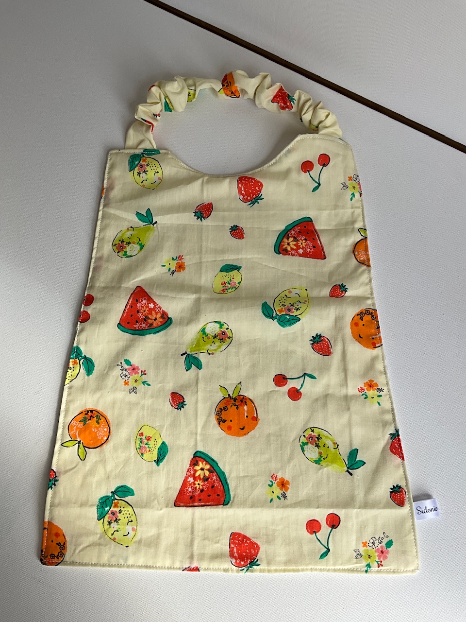 Serviette de cantine enfant dès 3 ans à encolure élastiquée, motif Fruits d'été, coton imprimé et nid d'abeille