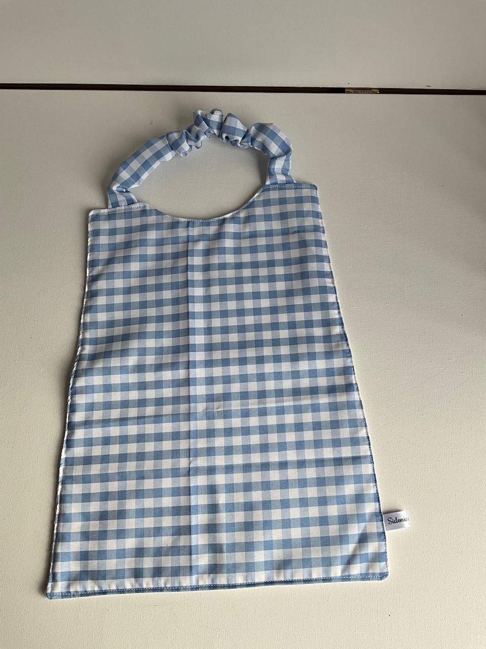 Serviette de cantine enfant dès 3 ans à encolure élastiquée, motif Vichy bleu ciel, coton imprimé et nid d'abeille