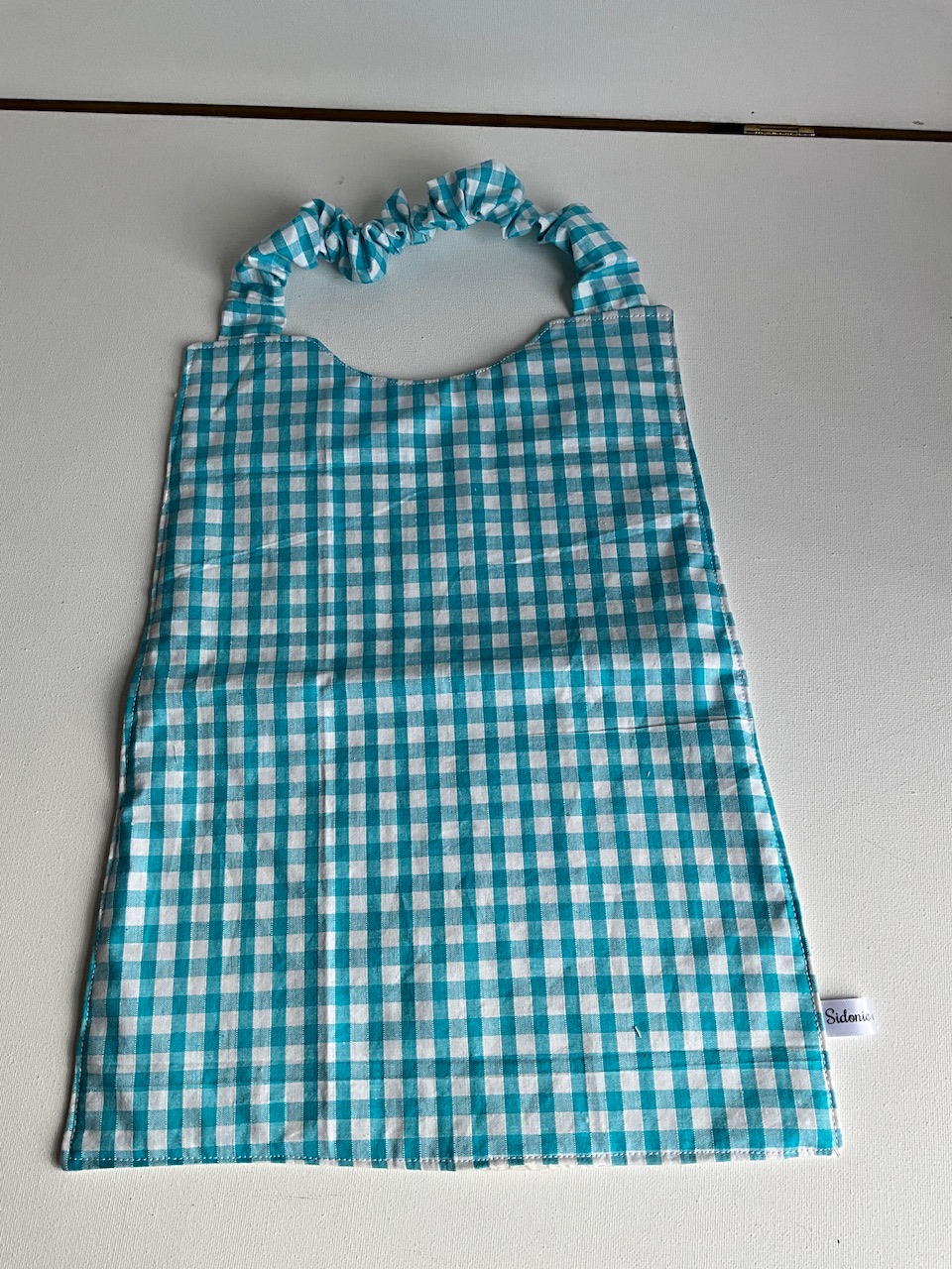 Serviette de cantine enfant dès 3 ans à encolure élastiquée, motif Vichy turquoise, coton imprimé et nid d'abeille